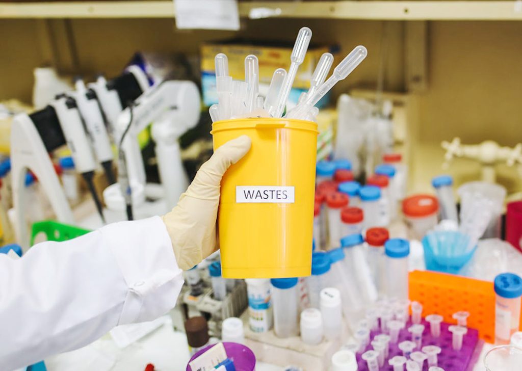 A person holding a container containing laboratory waste