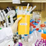 A person holding a container containing laboratory waste