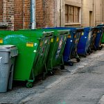 Multiple industrial bins lined up outside some buildings