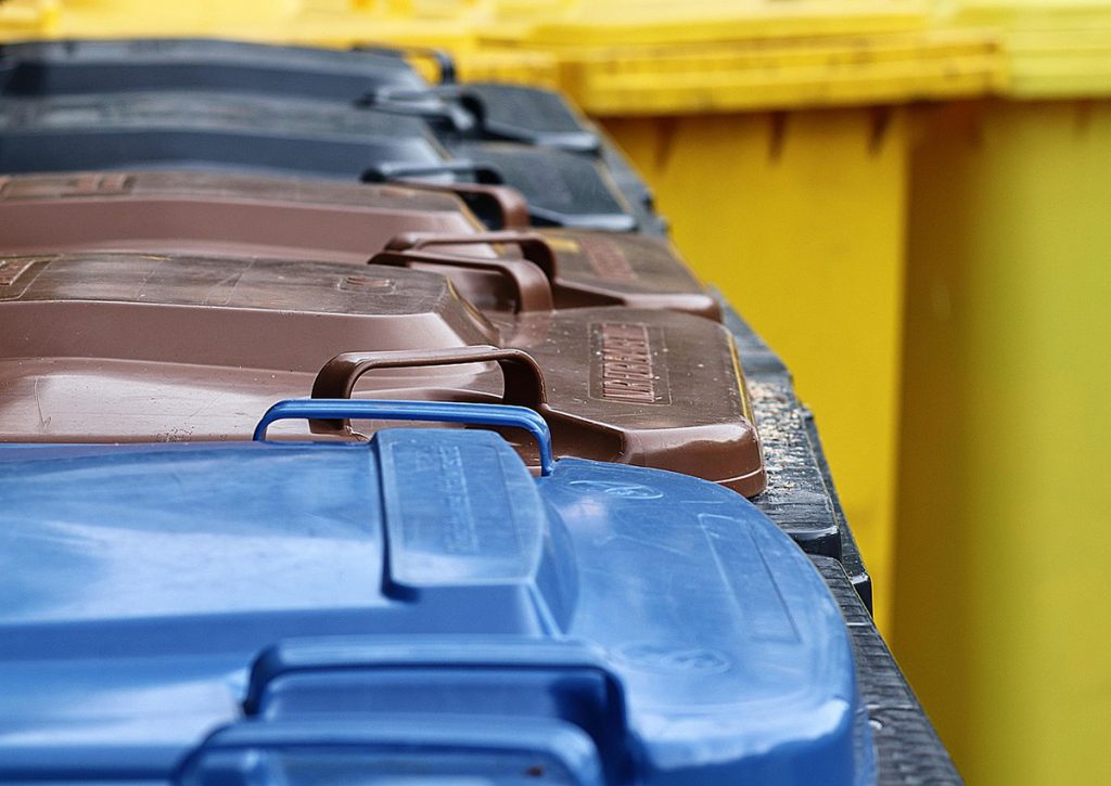 A collection of various coloured wheelie bins outside