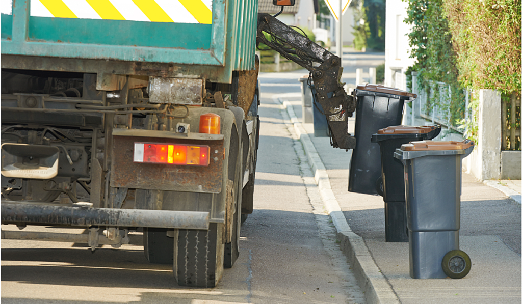 A garbage truck picking up garbage bins on the street