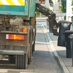 A garbage truck picking up garbage bins on the street