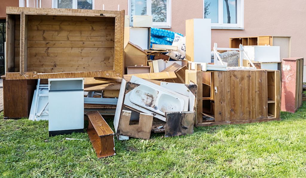 Pile of old furniture, cabinetry and household rubbish collected outside a home for professional rubbish removal.