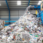 Large pile of mixed paper and cardboard materials being processed at a recycling facility.