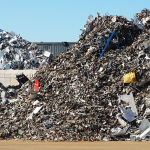 Large piles of scrap metal and recyclable materials at a recycling depot ready for sorting and processing.