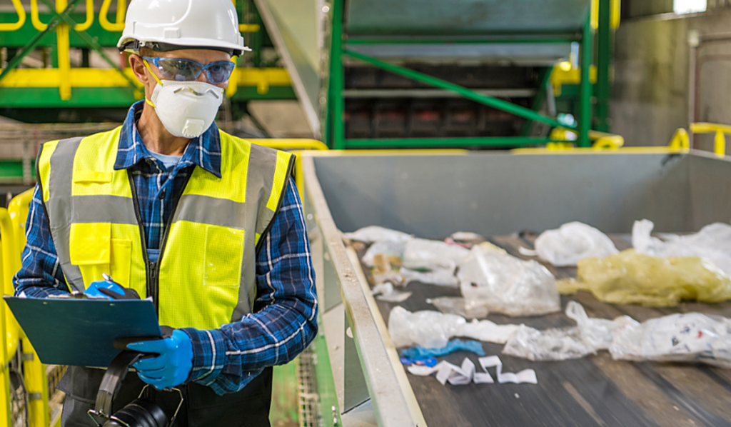 Worker conducting a waste audit at a recycling facility