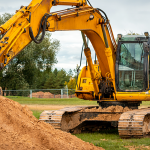 Yellow excavator moving a pile of soil at a construction site.